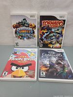 Four Nintendo Wii games in their cases: Skylanders Giants, Tornado Outbreak, Angry Birds Trilogy, Rise of the Guardians, arranged on a surface.