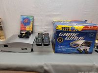 Game Wave console, two remote controllers, video game disc, cables, and original box displayed on a table.