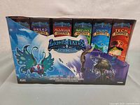 Photo of the front side of the Lightseekers Awakening TCG booster display box showing six sealed starter decks of different elemental themes including Dread, Mountain, Nature, Storm, and Tech.