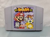 Front view of Nintendo 64 Super Smash Bros. game cartridge showing the label featuring Mario and game title with visible wear and tear.