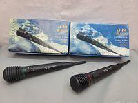 Pair of two wireless microphones alongside their original boxes showing the product image and branding.
