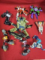 Full overview of all nine Transformers figures displayed on red cloth.