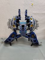 Front view of the Transformers Unicron figure in partially opened configuration showing mechanical and sculpted blue and silver parts with yellow details and spikes