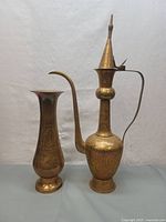 Full view of brass teapot and pitcher side by side against neutral background showing shape and size