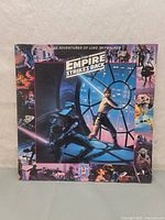 Front cover of The Empire Strikes Back vinyl record showing Luke Skywalker and Darth Vader artwork with film stills on border.