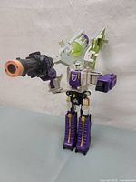 Front-side angled view of Voyager Class Megatron Transformers Classics Robots In Disguise toy figure holding a large black and orange cannon accessory, showing details on head, arms, torso, and legs.