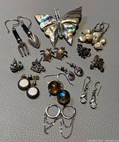 Lot overview showing butterfly brooch and various pairs of earrings including pearl cluster drops, turtle studs, and gardening tool shaped earrings