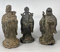 Front view of all three deity figurines side by side on neutral background.