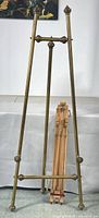 Full view of brass floor easel with wooden easel stand behind