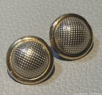 Front view of pair of round dome earrings with textured pattern and smooth gold border
