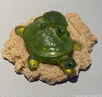 Close-up image of green carved and polished tortoises on a beige sandstone base showing surface texture and detail