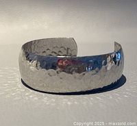 Front angled view of the silver tone hammered open cuff bangle showing its textured surface and reflective finish.