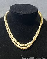 View of the two-strand pearl necklace displayed on a black bust showing the pearl arrangement and length.