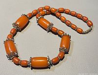 Photo showing the necklace laid flat highlighting the combination of large barrel and smaller round Bakelite beads separated by decorative metal spacers