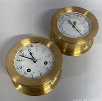 Top view of vintage brass German ship clock and barometer set on white surface