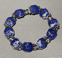 Top view of blue enamel bracelet showing ten linked panels with silver-tone Siam temple dancer figures.