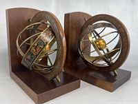 Pair of vintage wooden bookends each with armillary zodiac sphere mount, showing side and angled views.