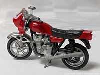 Left side view showing red body, silver engine, wheels, and black seat