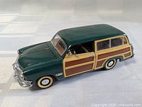 Front left view of green woodie wagon die-cast model showing grille, wood panel sides, whitewall tyres