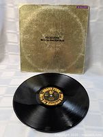 Vinyl LP on top of gold sleeve showing label and cover