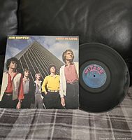 Photo showing the vinyl record partially out of its album cover featuring Air Supply band members in front of a tall glass building.