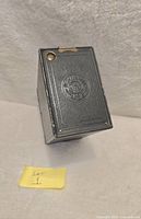 Front angled view of camera showing embossed Kodak No. 2A Brownie logo, leatherette texture and metal fitting details.