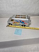 Side and top views of silver diecast van approx. 4.75" long with Superman 'Supervan' graphics and clear windows on roof revealing interior.