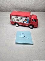Front-left angle view of red vintage toy truck showing the 'Daily Planet Superman Saves The World' side graphic featuring Superman image.