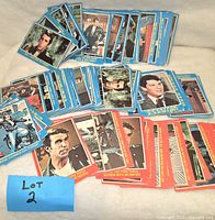 View of assorted collectible cards laid out to show quantity and variety including blue and red bordered cards with images and text.