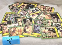 Photo showing a scattered pile of collectible trading cards featuring characters and scenes with yellow borders.