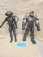 Full view of both 12-inch action figures, Black Manta on the left and Rhino on the right, standing upright on a neutral background.