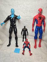 Front view of four Marvel action figures together on white background: large Electro, large Spider-Man, smaller crouching Spider-Man, and Black Panther standing
