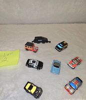 Photo showing all seven vintage Micro-Machines toy cars on a white surface from overhead angle.