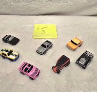 Overview of all 7 Micro Machines toy vehicles shown on a white surface with sticky note 'Lot 3'