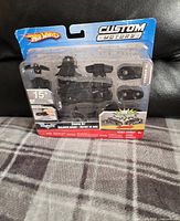 Front view of the Hot Wheels Custom Motors Batmobile set in sealed packaging showing all the parts inside.