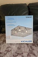 Front of the box showing the Kichler brand and image of the flush mount ceiling light fixture with round decorative accents on a grid pattern.