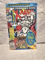 Front of a sealed comic book The Uncanny X-Men #296 showing a silver-armored character with red cape and promotional blue circle for included trading card