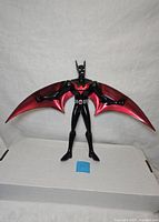 Front view of Batman Beyond After Burner figure with wings spread, showing red and black color scheme and bat emblem on chest.