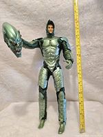 Green Goblin action figure holding the green goblin mask in hand, showing the stitched material costume and armor details.