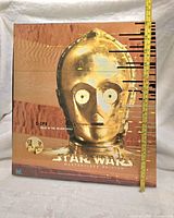 Front side of the boxed set showing C-3PO head graphic and box size with tape measure.