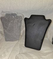 Front view of the two jewelry display stands, one black faux leather and one gray felt enclosed in plastic wrapping.