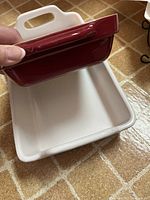 Red ceramic baking dish being held to show size and details