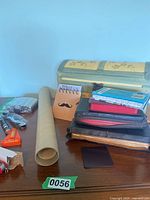 Wide view of table showing Bibles, notebooks, unopened packaging, rolled paper, and decorative chest