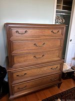 Front view of the solid wood dresser showing five drawers with metal handles and decorative molding.