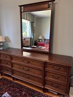 Front view of 9 drawer solid wood dresser with large attached mirror reflecting room.