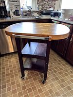 Front view of assembled kitchen island showing butcher block top, two shelves and casters