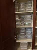 Cabinet shelves containing multiple Lock & Lock plastic food storage containers in various sizes and shapes stacked neatly.