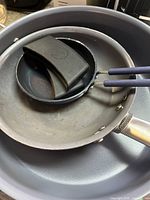 Three frying pans stacked together showing different sizes and materials.