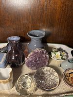 Full view of amethyst piece with paperweights and vases on white tray inside wooden shelf