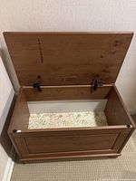 Open wooden storage bench showing inside storage compartment lined with floral patterned paper.